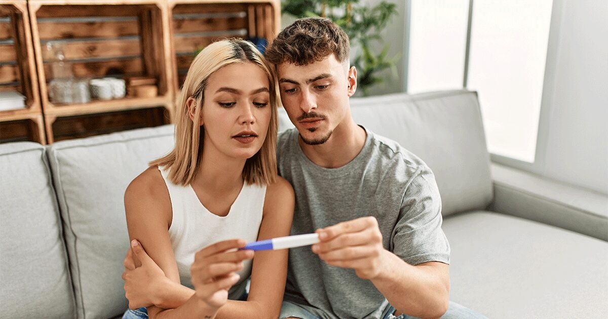 Expectant father supports his partner as they look at a pregnancy test and prepare for parenthood.